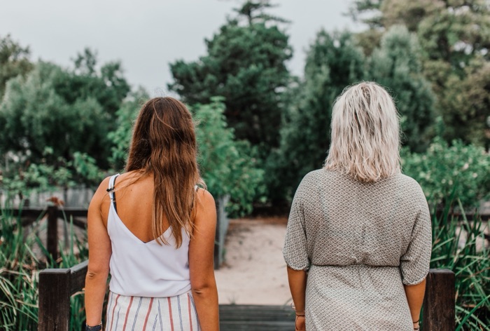 Two women standing side by side, looking down a path ahead