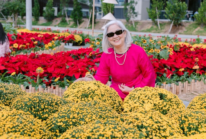 A smiling woman standing among beds of yellow and red flowers