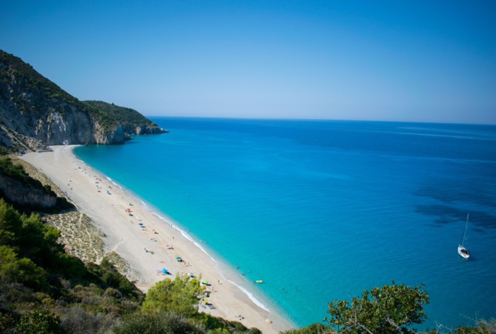 A curved beach of white sand meeting turquoise sea